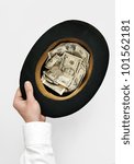 Small photo of Cadger concept. Hand holding old top-hat with money isolated on white background from top view.