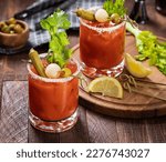 Small photo of Bloody mary cocktail garnished with celery, okra, onion, olive and salt rim on a rustc wooden table