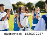 Small photo of Happy football players hugging on field after scoring a goal. Soccer teammates embracing while players clapping hands on victory. Successful girl soccer players celebrating after winning the match.