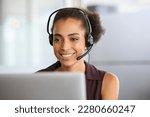Small photo of Call center agent with headset working on support hotline in office. Black businesswoman in conversation with customer during video call. African american business woman working remotely on laptop.