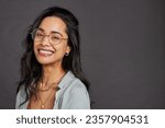 Casual cheerful young woman with eyeglasses smiling at camera on gray background. Close up face of happy multiethnic girl laughing with trendy eyeglasses and copy space. Beautiful mixed race girl.