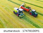 Aerial drone view of harvest. Combine harvester and tractor with carriage on the field. Winter crop harvesting