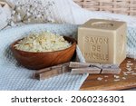 Small photo of Quimper, Brittany France November 10 2021: Marseille soap bar named Savon de Marseille in french and grated soap on the cotton towel with clothes pegs and washing brush at home laundry room close up.