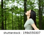 Side view portrait of an asian woman breathing fresh air in a forest