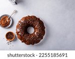 Small photo of Chocolate bundt cake drizzled with chocolate ganache glaze and chocolate shavings overhead with copy space