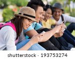 Friends sitting in the park and using their smartphones