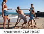 Small photo of Joyful family ing limbo on sandy beach