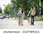 Citizens wearing sunglasses and medical masks when crossing road with bicycles