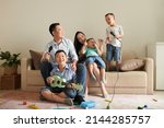 Small photo of Happy Asian family of five laughing, playing ukulele and singing song into microphone