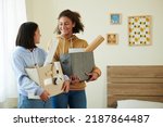Small photo of Smiling teenage roommates with boxes of belongings meeting each other for the first time
