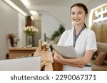 Small photo of Portrait of smiling spa salon receptionist with documents folder