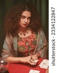 Small photo of Portrait of fortune teller shuffling tarot cards and looking at camera