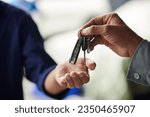 Closeup image of mechanic giving car keys to client after repairing it