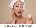 Excited woman applying nourishing cream after morning shower