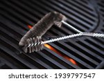 Small photo of Cleaning outdoor gas grill with a metal brush before next grilling. Close-up.