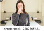 Small photo of young adult pretty woman feeling disgusted, holding nose to avoid smelling a foul and unpleasant stench