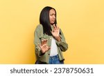 Small photo of young black woman feeling disgusted and nauseous, backing away from something nasty, smelly or stinky, saying yuck