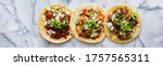 row of mexican street tacos with carne asada and al pastor in corn tortilla wide banner composition