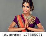 Portrait of a beautiful indian girl in a greetting pose to Namaste hands .India woman in traditional sari dress and jewelry.