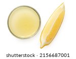 Small photo of Freshly squeezed lemon juice in a glass bowl next to lemon segment isolated on white. Top view.