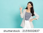 Young beautiful Asian business woman pointing to empty copy space isolated on green background