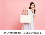 Happy Asian woman holding white textile eco bag isolated on pink background, Ecology or environment protection concept