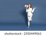 Small photo of Young Asian business woman in white suit holding megaphone isolated on blue background, Speech and announce concept, Full body composition