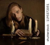 Small photo of long-haired man thought about something after breaking away from reading an old book by candlelight