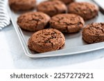 Freshly baked double chocolate chip cookies on a baking sheet.