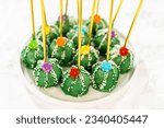 Small photo of Cactus-shaped cake pops, beautifully decorated with luster dust, sugar flowers, and white sprinkles, arranged in celebration of Cinco de Mayo.