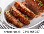 Small photo of Slicing classic meatloaf with a sweet glaze on a white serving plate
