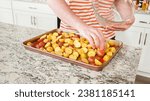 Small photo of In a modern, white kitchen, a young man is engrossed in dinner preparations. His current endeavor includes arranging seasoned rainbow potatoes on a baking sheet, a meticulous step towards a