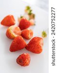 Small photo of Succulent red strawberries, some showing early spoilage, are arrayed on a white cutting board, held securely in place, with a paper towel lined glass bowl nearby suggesting an attempt at preservation.