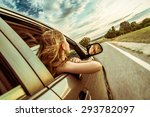 Happy beautiful girl traveling in a car across Europe with focus in front of the car