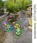 Small photo of Helen, GA USA - September 9, 2023: Elevated perspective shows people tubing on the Chattahoochee River on a hot summer day on September 9, 2023 in Helen, GA.