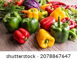 Colorful green , red and yellow peppers paprika  and other vegetables on a wooden table 
