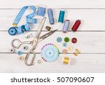 Tools and accessories for sewing on light wooden background. Top view.