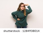 Teenager girl over white wall looking far away with hand to look something