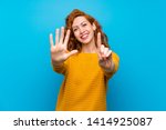 Redhead woman with yellow sweater counting six with fingers