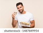 Handsome man holding muffin cake over isolated background