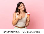 Young caucasian woman with a cornet ice cream isolated on pink background giving a thumbs up gesture