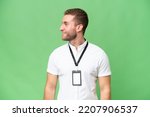 Young caucasian man with ID card isolated on green chroma background looking side