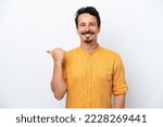 Small photo of Young man with moustache isolated on white background pointing to the side to present a product