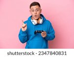 Small photo of Young brazilian man playing with a video game controller isolated on pink background intending to realizes the solution while lifting a finger up