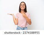 Young caucasian woman isolated on white background holding copyspace imaginary on the palm to insert an ad and with thumbs up