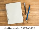 blank notebook with pen and pencil on wooden table, business concept