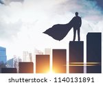 Silhouette of a businessman in a cape standing on a giant bar chart and looking at a modern cityscape. Toned image double exposure mock up