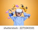 Small photo of Astonished little boy in VR goggles standing over blue orange with videogames and multimedia icons above him. Concept of internet for joy