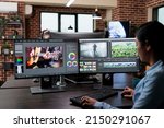 Creative company professional movie footage editor sitting at multi monitor workstation while editing film frames. Expert videographer improving video quality using specialized software.
