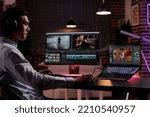 Asian editor working on movie production with computer software, editing film montage with audio and visual effects. Creating multimedia content with footage, color grading creative app.